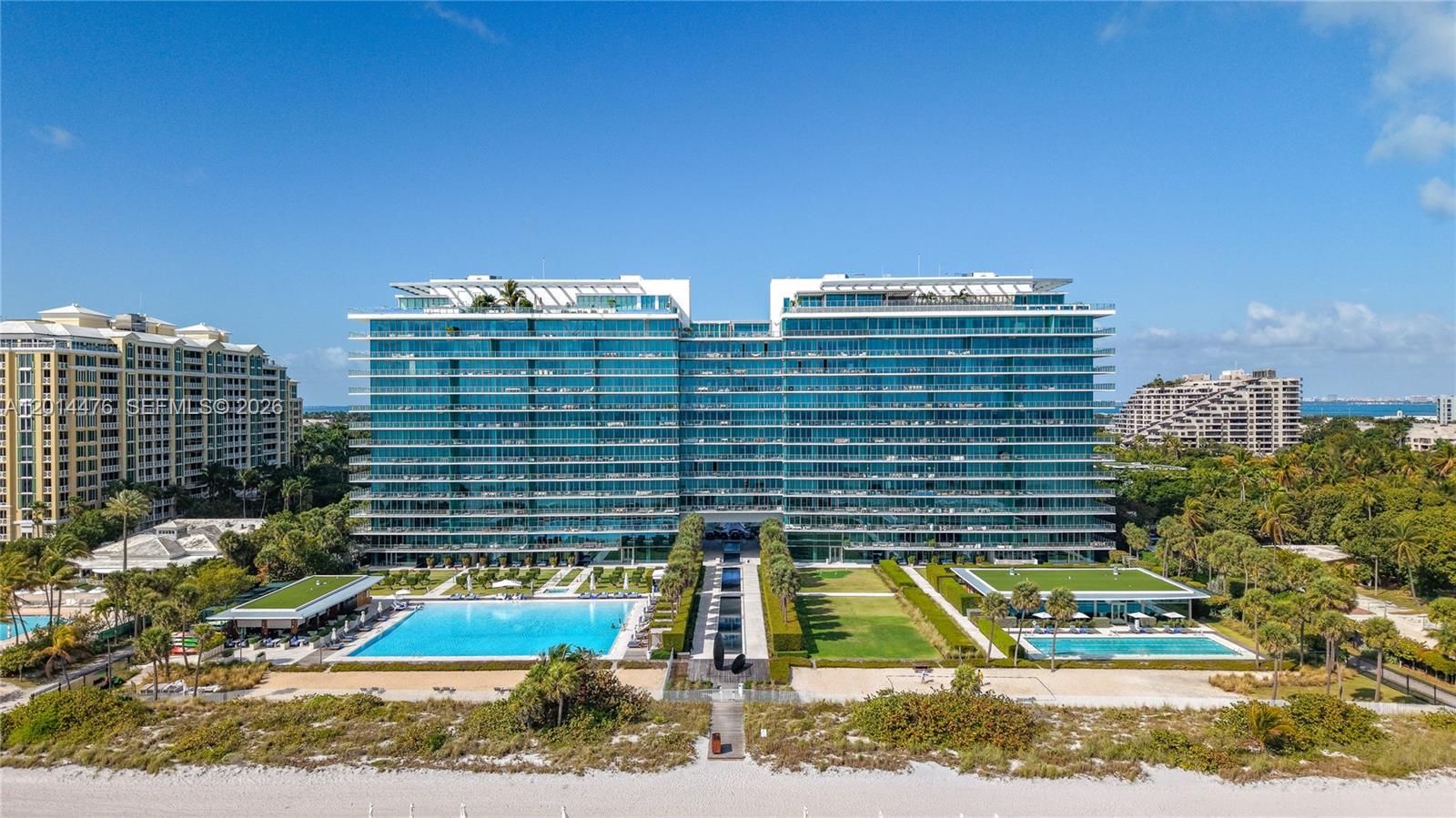 360 Ocean Drive, Unit 1106S Key Biscayne, FL 33149 - Photo 46 of 67 Aerial Building Front – A centered aerial view showcases the full building façade, resort-style pool areas, landscaped lawns, and direct beach approach. The symmetrical layout creates a clean, impressive presentation of the property.