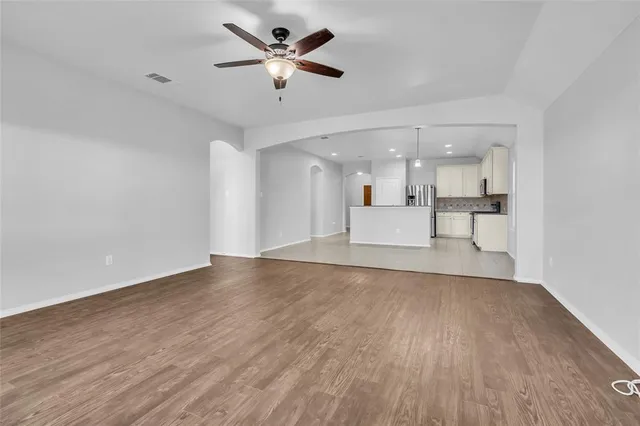 a view of a kitchen with a dishwasher a kitchen island hardwood floor and a ceiling fan