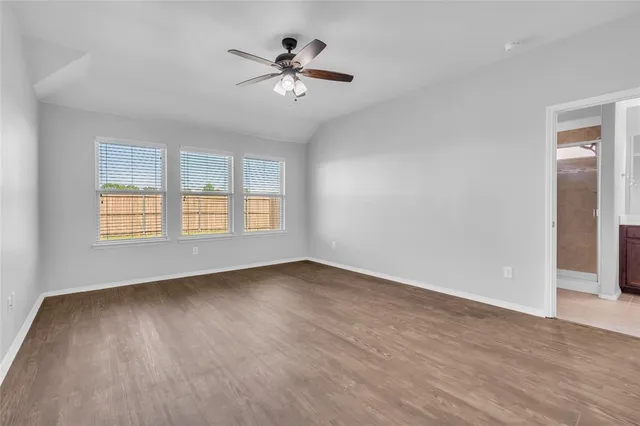 an empty room with wooden floor chandelier fan and windows