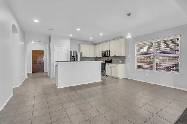 a view of kitchen with stainless steel appliances granite countertop a stove top oven a refrigerator a sink and a cabinets