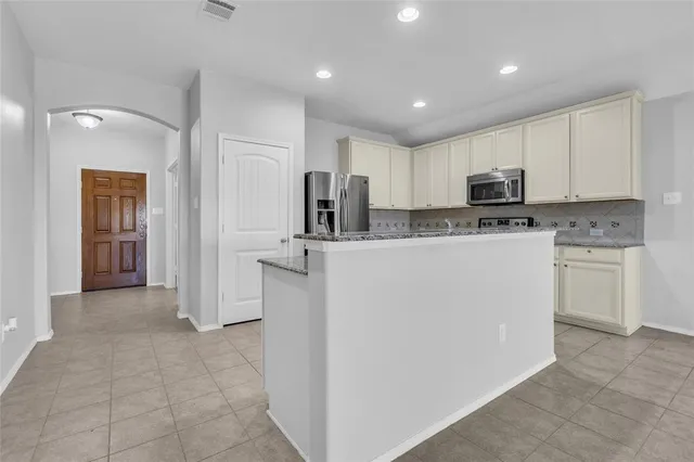 a kitchen with kitchen island a white counter top space stainless steel appliances and cabinets