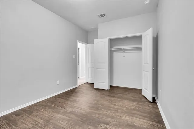 a view of an empty room with wooden floor and closet