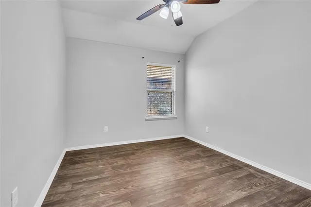 an empty room with a chandelier fan and windows