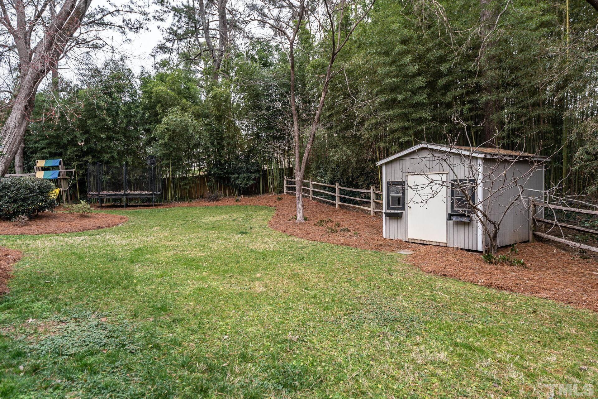 2204 West Charlotte Court Raleigh, NC 27607 - Photo 29 of 31 a view of a backyard with a slide trees and wooden fence