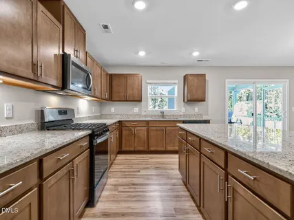 a kitchen with stainless steel appliances granite countertop sink stove microwave and cabinets
