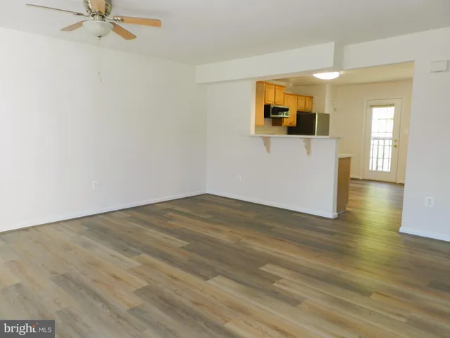 a view of a room with wooden floor and a ceiling fan