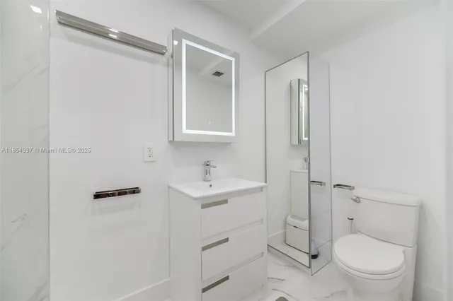 a bathroom with a toilet sink vanity and mirror