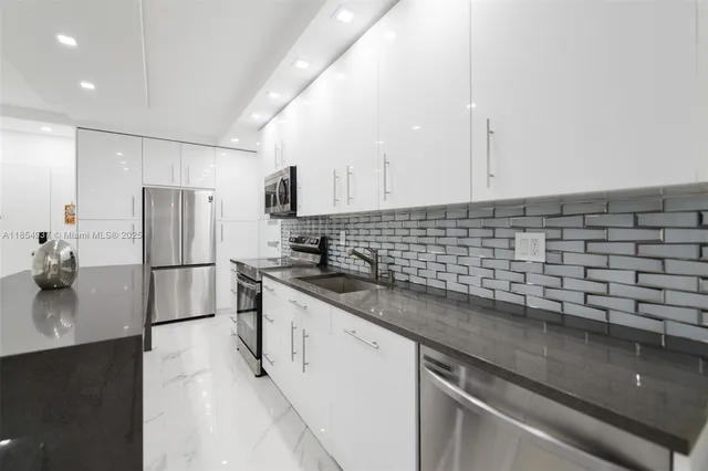 a kitchen with granite countertop a sink stainless steel appliances and white cabinets