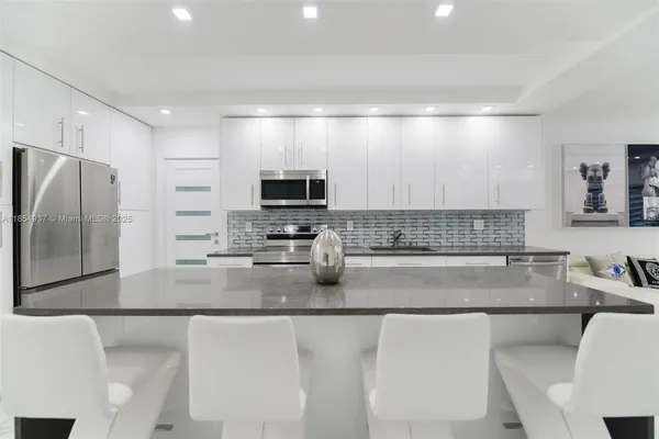 a kitchen with stainless steel appliances a sink a stove a microwave a refrigerator a counter top space and cabinets