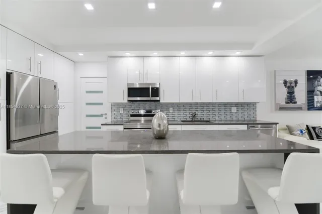 a kitchen with stainless steel appliances a sink a stove a microwave a refrigerator a counter top space and cabinets