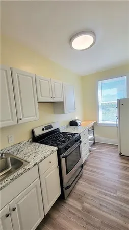 a kitchen with granite countertop a stove a sink and a refrigerator