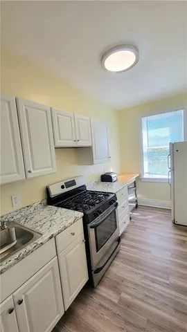 a kitchen with granite countertop a stove a sink and a refrigerator