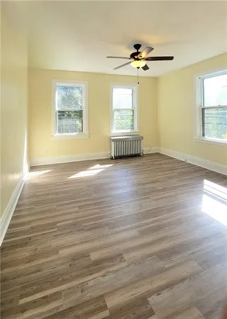 a view of an empty room with a window and wooden floor