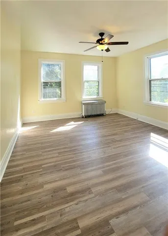 a view of an empty room with a window and wooden floor