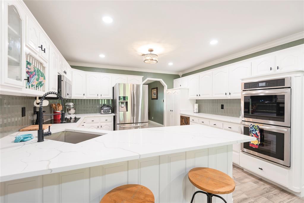 2020 Arbor Bend Road Bonham, TX 75418 - Photo 12 of 40 Kitchen featuring a peninsula, arched walkways, tasteful backsplash, stainless steel appliances, and ornamental molding