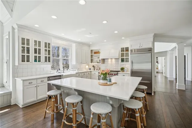 a kitchen with stainless steel appliances kitchen island granite countertop a dining table chairs and white cabinets