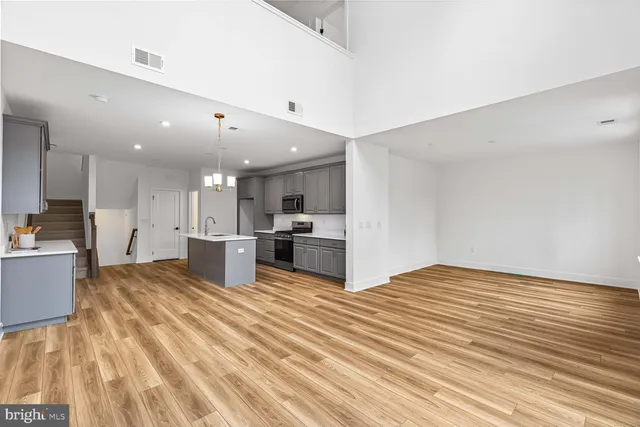 a large kitchen with kitchen island a stove a sink dishwasher and a refrigerator with wooden floor