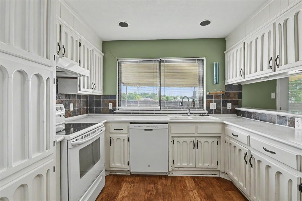 332 Cook Road Willow Park, TX 76087 - Photo 11 of 26 White cabinetry with decorative arch panels, dark tile backsplash, wood-finish flooring, and white appliances