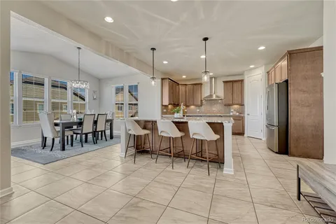 a large kitchen with kitchen island a dining table chairs and a refrigerator