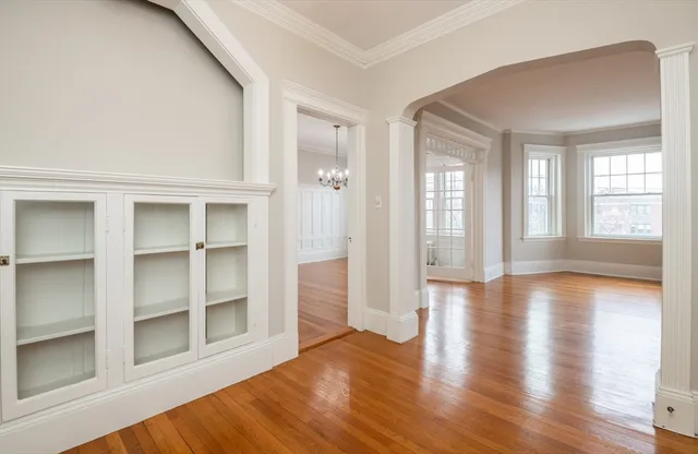 a view of an empty room with window and wooden floor