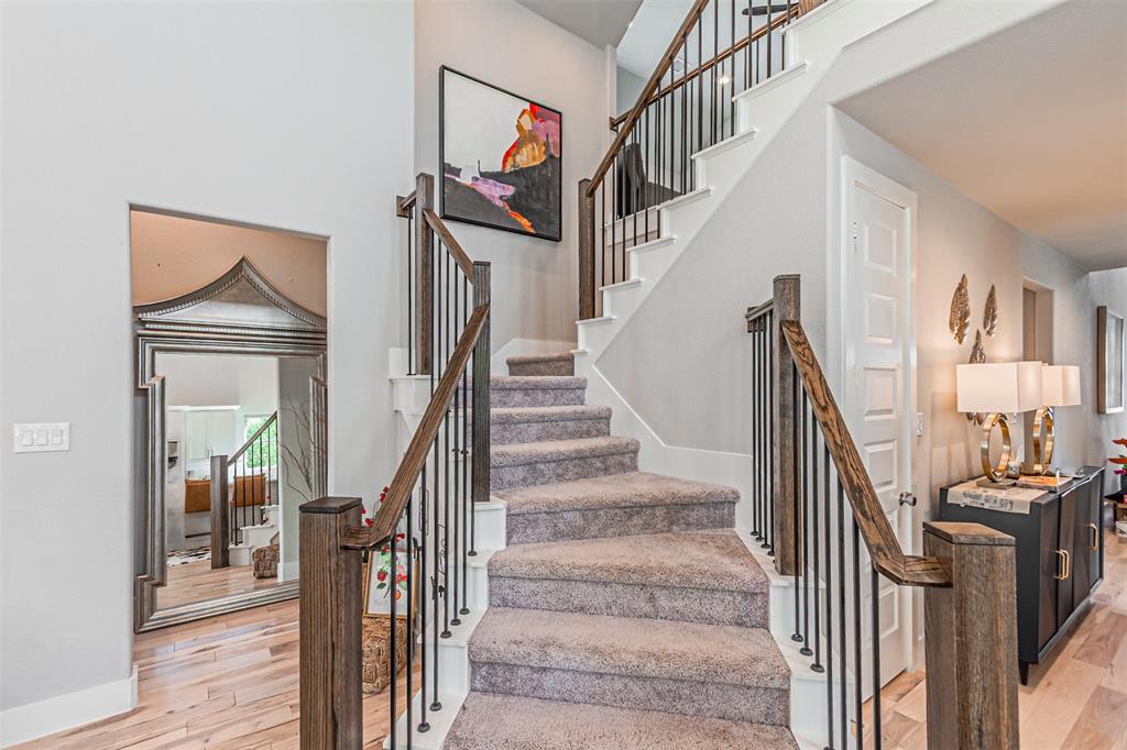1070 Adair Road Prosper, TX 75078 - Photo 31 of 40 Carpeted staircase with dark wood newel posts and handrails, complemented by black iron balusters