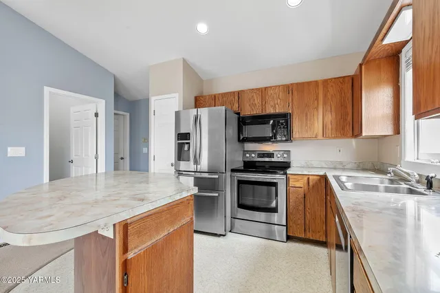 a kitchen with stainless steel appliances granite countertop a sink stove microwave and refrigerator