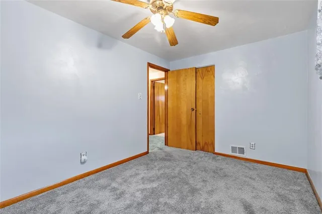 a view of an empty room with chandelier fan