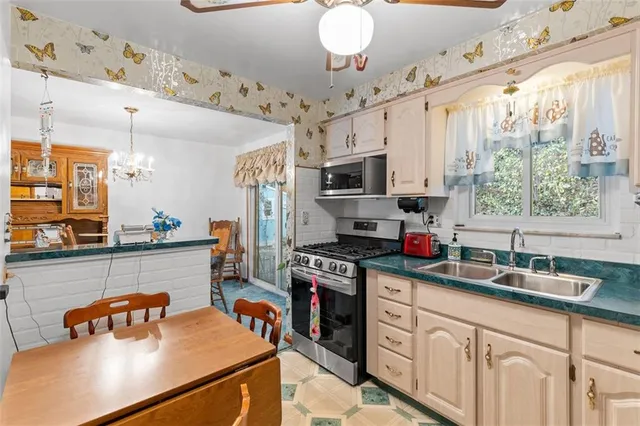 a kitchen with stainless steel appliances a sink a stove window and cabinets