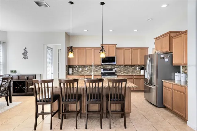 a kitchen with stainless steel appliances kitchen island granite countertop a table chairs and a refrigerator