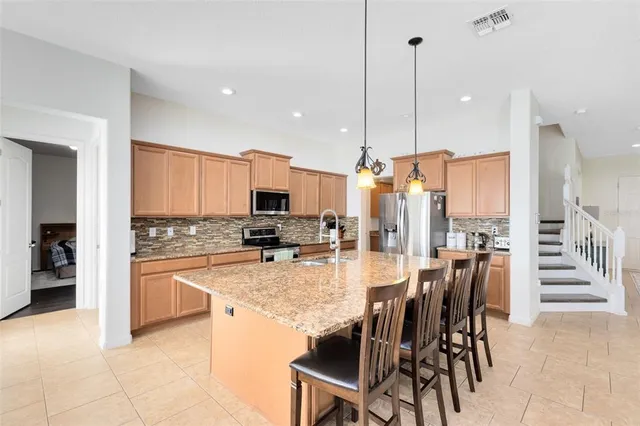 a kitchen with stainless steel appliances kitchen island granite countertop a table chairs sink and cabinets