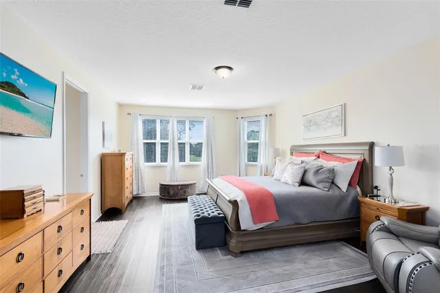 a spacious bedroom with a bed and wooden floor