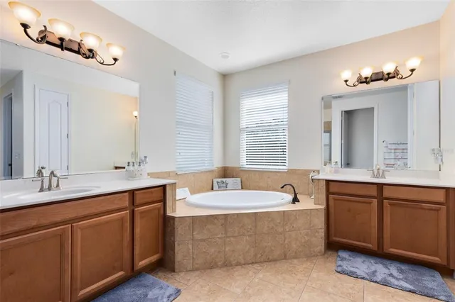 a spacious bathroom with a double vanity sink large mirror and a bathtub