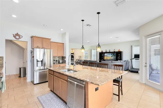 a kitchen with stainless steel appliances kitchen island granite countertop a refrigerator and microwave