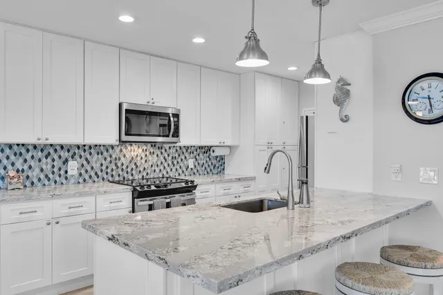 a kitchen with granite countertop a sink a stove and a microwave with wooden floor