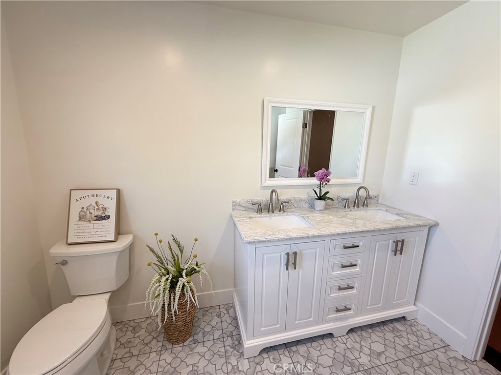 13302 Sandra Place Garden Grove, CA 92843 - Photo 21 of 41 a bathroom with a granite countertop toilet sink and mirror