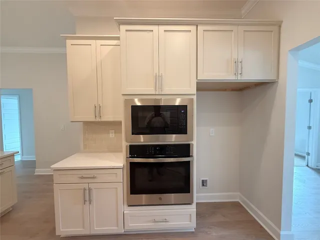 a kitchen with granite countertop white cabinets and stainless steel appliances