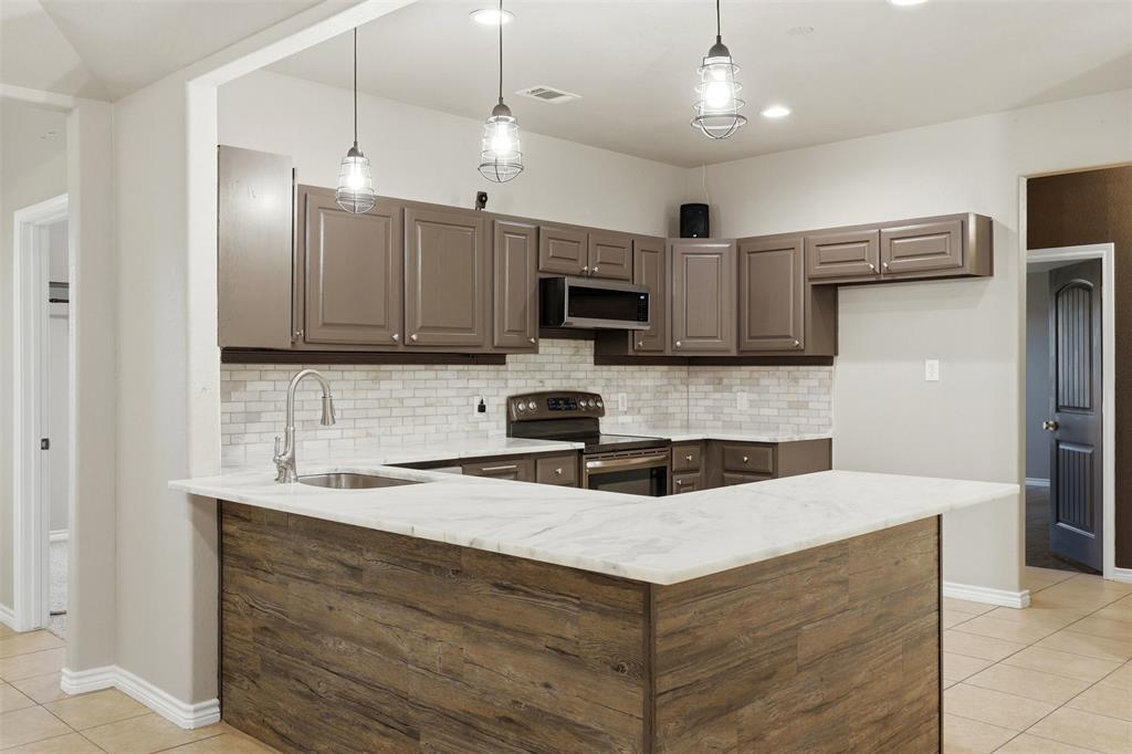 113 Mulkey Road Waxahachie, TX 75167 - Photo 6 of 39 a kitchen with kitchen island a sink stainless steel appliances and cabinets