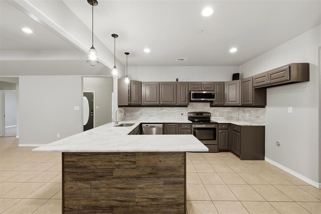 113 Mulkey Road Waxahachie, TX 75167 - Photo 7 of 39 a large kitchen with granite countertop a stove a sink dishwasher a refrigerator and a oven with wooden floor