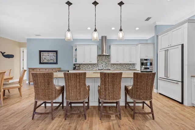 a kitchen with stainless steel appliances granite countertop a dining table chairs refrigerator and wooden floor