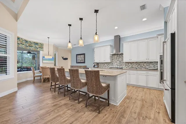 a large kitchen with kitchen island granite countertop a stove a sink a dining table and chairs