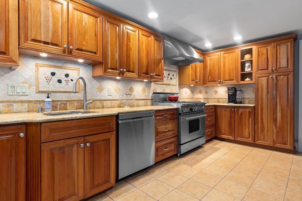 94 Conant Street Danvers, MA 01923 - Photo 13 of 36 a kitchen with stainless steel appliances granite countertop a stove top oven a refrigerator a sink and dishwasher with wooden cabinets