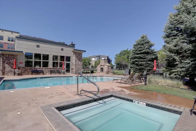 a view of swimming pool with outdoor seating and house in the background