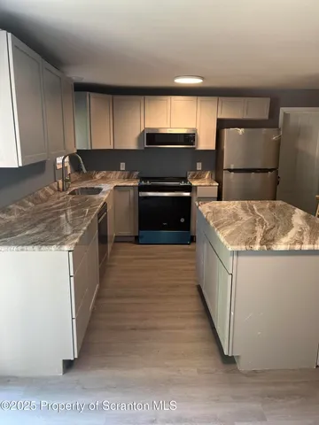 a kitchen with kitchen island granite countertop a sink a counter top space and cabinets