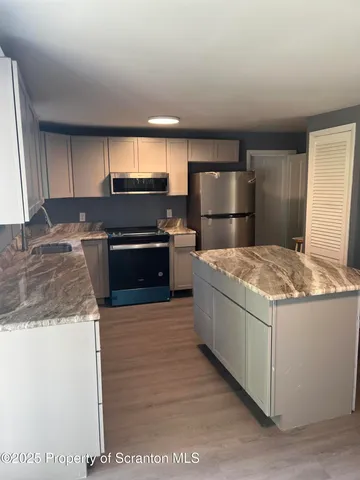 an empty room with wooden floor fireplace and windows