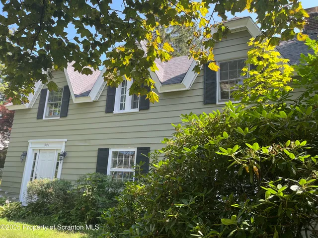 a front view of a house with a tree
