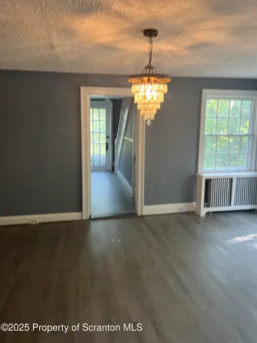 an empty room with wooden floor fireplace and windows