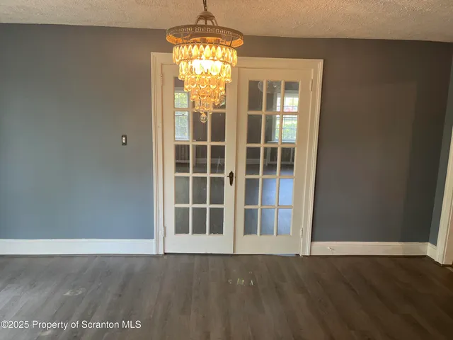 an empty room with wooden floor mirror and windows