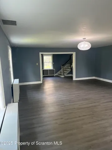 an empty room with wooden floor fireplace and windows