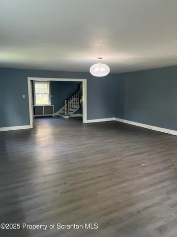 an empty room with wooden floor and windows with curtains