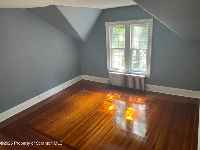 a view of an empty room with wooden floor and closet